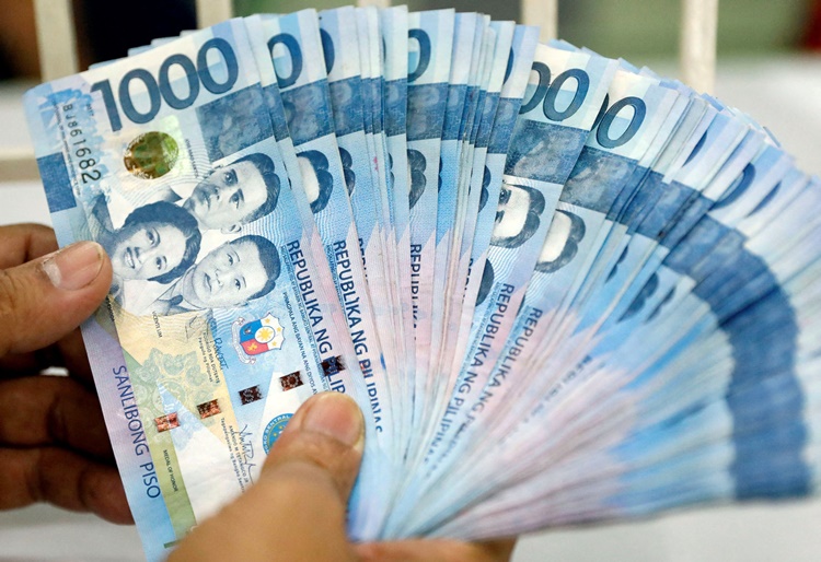 File photo: a worker shows philippine peso bills inside a money changer in metro manila