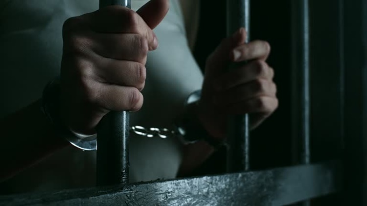 Close up, women holdin prison bars at prison cell