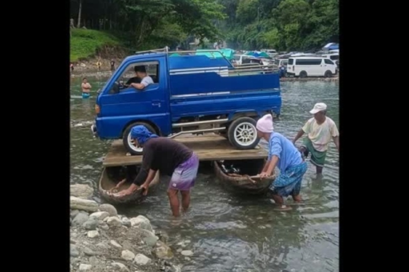 Truck floats on makeshift ferry using two wooden boats to cross river in Rizal