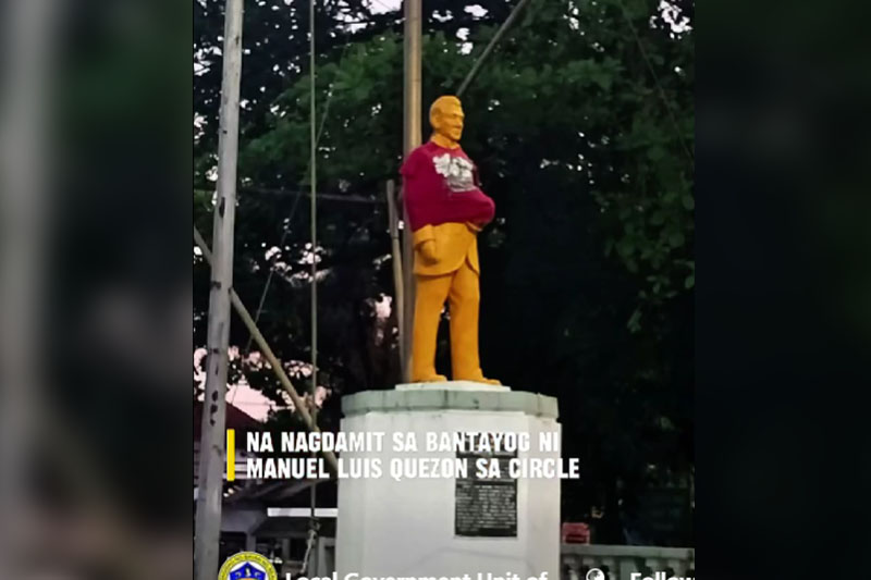 マニュエル・ケソン像に自らのシャツ着せる男性